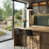 Two wood bar stools with black frames and supportive backrests at a modern kitchen island beside a garden window by sackit