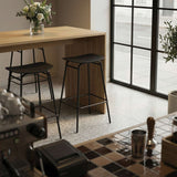 sackit bar stool with a black metal frame and curved seat beside a wooden kitchen island in a bright Nordic interior with large windows and plants