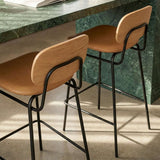 Industrial-style bar stool with leather seat and backrest, powder-coated steel frame, and footrest.