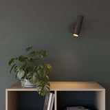 Black Expo Wall light with aluminum base mounted on a white wall in a minimalistic setting.