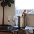 Satin polished stainless steel wine cooler with leather handle and included ice tong on a white background