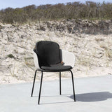 Outdoor patio chair with a full slipover cushion in black on a wooden deck setting.