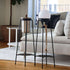 Black powder-coated stainless steel Patio Accessory Stand with a small light on top, shown outdoors on a wooden surface.
