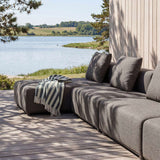 sackit Cobana outdoor lounge sofa in charcoal fabric with chaise and striped throw on a wooden terrace overlooking a calm Nordic lake