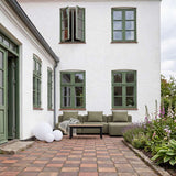 Olive green three seat outdoor lounge sofa with clean Scandinavian lines, styled with a black coffee table in a flower filled courtyard by sackit