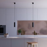 Black aluminum Expo Pendant light with slim cylindrical design and long black cord hanging indoors.