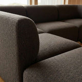 Close up of a dark brown Fjord corner sofa with a rounded armrest and soft textured upholstery in a calm Scandinavian interior by sackit