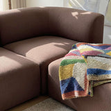 Brown Fjord corner sofa with rounded cushions and a colorful woven throw in a sunlit Scandinavian living room