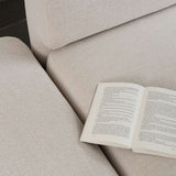 Close view of a light fabric Fjord Sofa with an open book resting on its soft cushions showcasing calm Scandinavian design by sackit