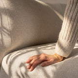 Close up of a hand resting on the soft textured upholstery of the Fjord corner sofa in warm sunlight by sackit for calm Scandinavian comfort