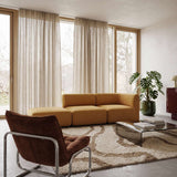 Mustard yellow sackit Fjord two seater sofa with open end in a bright Scandinavian living room beside a glass coffee table and textured rug