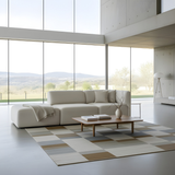 Cream two seat sofa with an open end and soft cushions in a bright Scandinavian living room with floor to ceiling windows and a modern coffee table by sackit