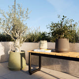 Matte ceramic outdoor planter with fluted surface inspired by ancient Greece, shown in natural setting