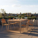 Outdoor teak dining table with six chairs arranged on a rooftop terrace overlooking a city skyline by sackit Europe