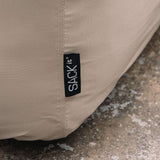 Close up of a sand colored water repellent cover for a Cobana Lounge Sofa with stitched seams and a black sackit label protecting outdoor furniture