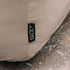 Close up of a sand colored water repellent cover for a Cobana Lounge Sofa with stitched seams and a black sackit label protecting outdoor furniture