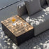 Outdoor storage coffee table with a warm wood slatted top beside a grey lounge sofa holding a pitcher and glasses in dappled sunlight from sackit