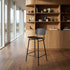 Black wooden bar stool with curved backrest and footrest in a warm modern kitchen by sackit