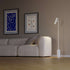 White Expo Floor lamp with aluminum body and marble base standing on a wooden floor.