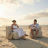 Two people relax on sackit soft outdoor sofa modules on a sandy beach at sunset showing comfortable frameless seating designed for outdoor living