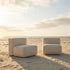 Two beige sackit Soft Sofa Outdoor modules arranged on a sandy beach overlooking the sea in warm evening light