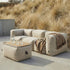 Beige outdoor pouf with a wooden tray beside a matching lounge sofa and blanket in a Nordic garden setting by sackit