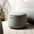 Dark blue Cura Pouf with soft fabric and round shape on a light background