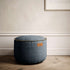Round Canvas Pouf in petrol color with hand-sewn linen stitches on a white background