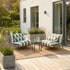Outdoor lounge chairs with striped bolster cushions on a sunlit patio beside potted grasses and a small round table from sackit