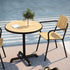 Round outdoor café table with teak wood top and black powder-coated aluminum base on a patio setting