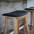 Nordic bar stool in oak with Luna Carbon leather upholstery and visible cross-stitching detail.