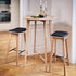 Nordic bar stool in Terra Black leather with oak wood and cross-stitch details, 73 cm height.