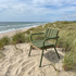 Green Kirra patio lounge chair with matching back cushion set among coastal dunes and beach grass beside the sea by sackit