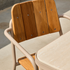 Outdoor dining chair with warm teak slat back and seat beside a rounded ceramic tabletop from sackit europe’s Kirra series