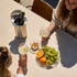 sackit outdoor dining table with wooden chairs and friends sharing fruit drinks and snacks in a sunny Nordic garden setting