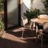 sackit Kirra outdoor dining set with a round teak table and four taupe patio chairs in a sunlit leafy courtyard