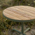 Round outdoor café table with teak wood top and powder-coated aluminum base in natural finish