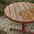 Round outdoor café table with teak wood top and powder-coated aluminum base on a terrace setting