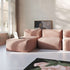 Pink ribbed three seat indoor sofa with a lounger in a bright living room featuring tall windows artwork and a floral rug by sackit