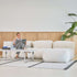 Cream indoor sofa with rounded cushions beside a coffee table and plant in a bright Scandinavian living room from sackit