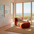 Orange indoor lounge sofa with matching ottoman in a coastal room overlooking the sea from sackit