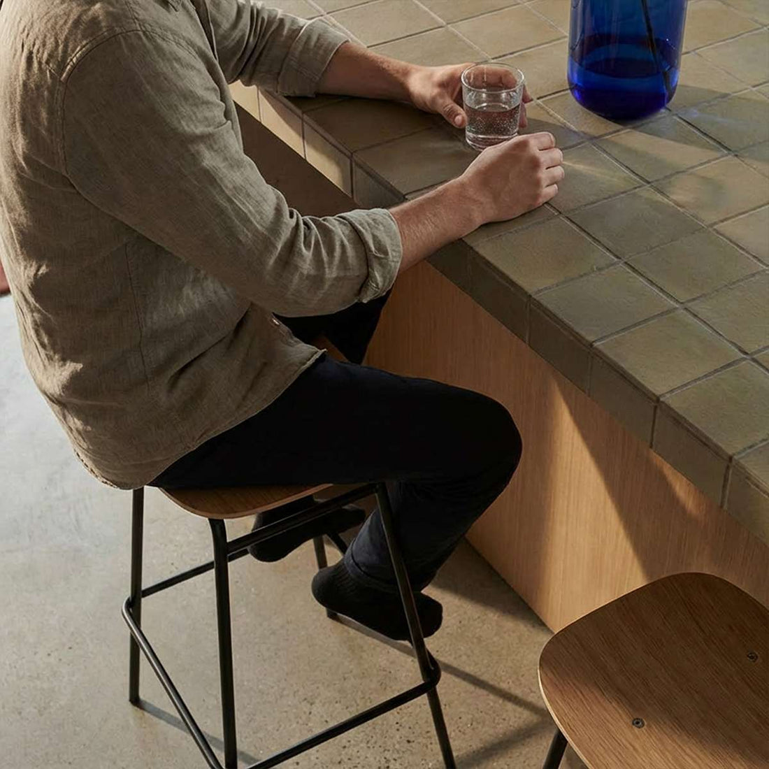 Bar stool with oak veneer seat and black powder-coated steel frame in industrial style.