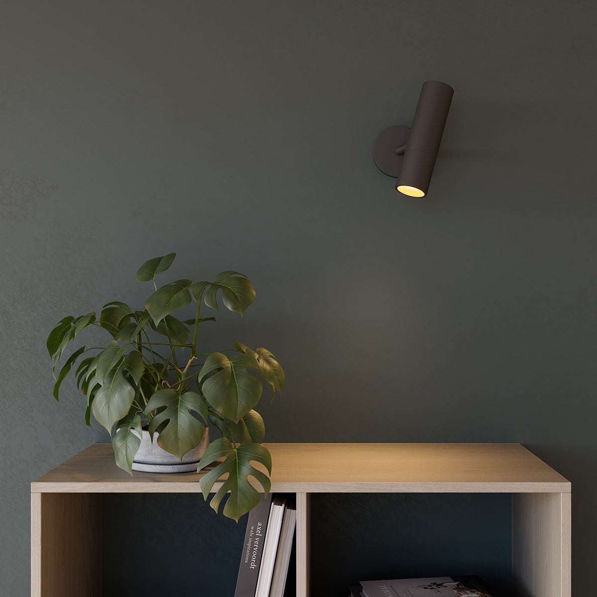 Black Expo Wall light with aluminum base mounted on a white wall in a minimalistic setting.