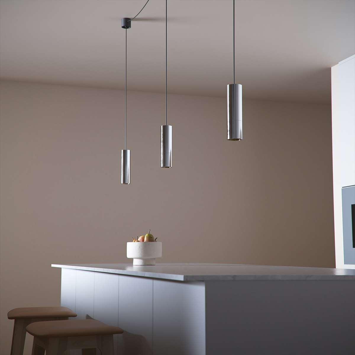 Polished aluminum Expo Pendant light with slim cylindrical shape and long black cord hanging indoors.