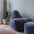 Round pouf with colorful striped Paul Smith cotton upholstery on a light floor background