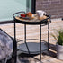 Outdoor patio serving table with teak wood tray and matte powder-coated steel frame in a sunny lounge setting