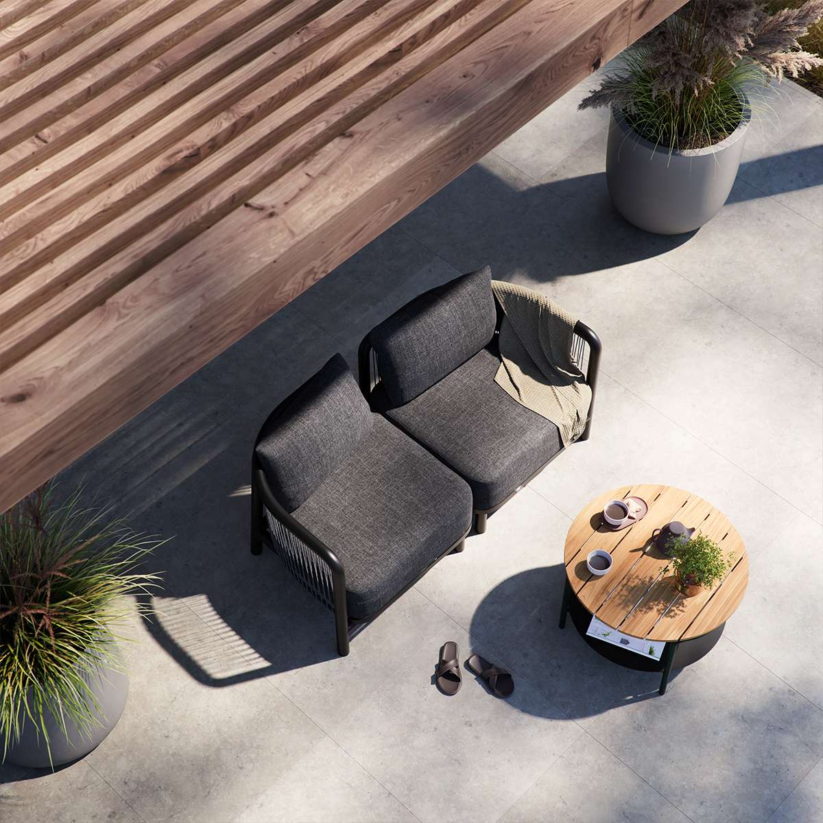 Round outdoor coffee table with black powder-coated aluminum base and teak wood tabletop on patio.