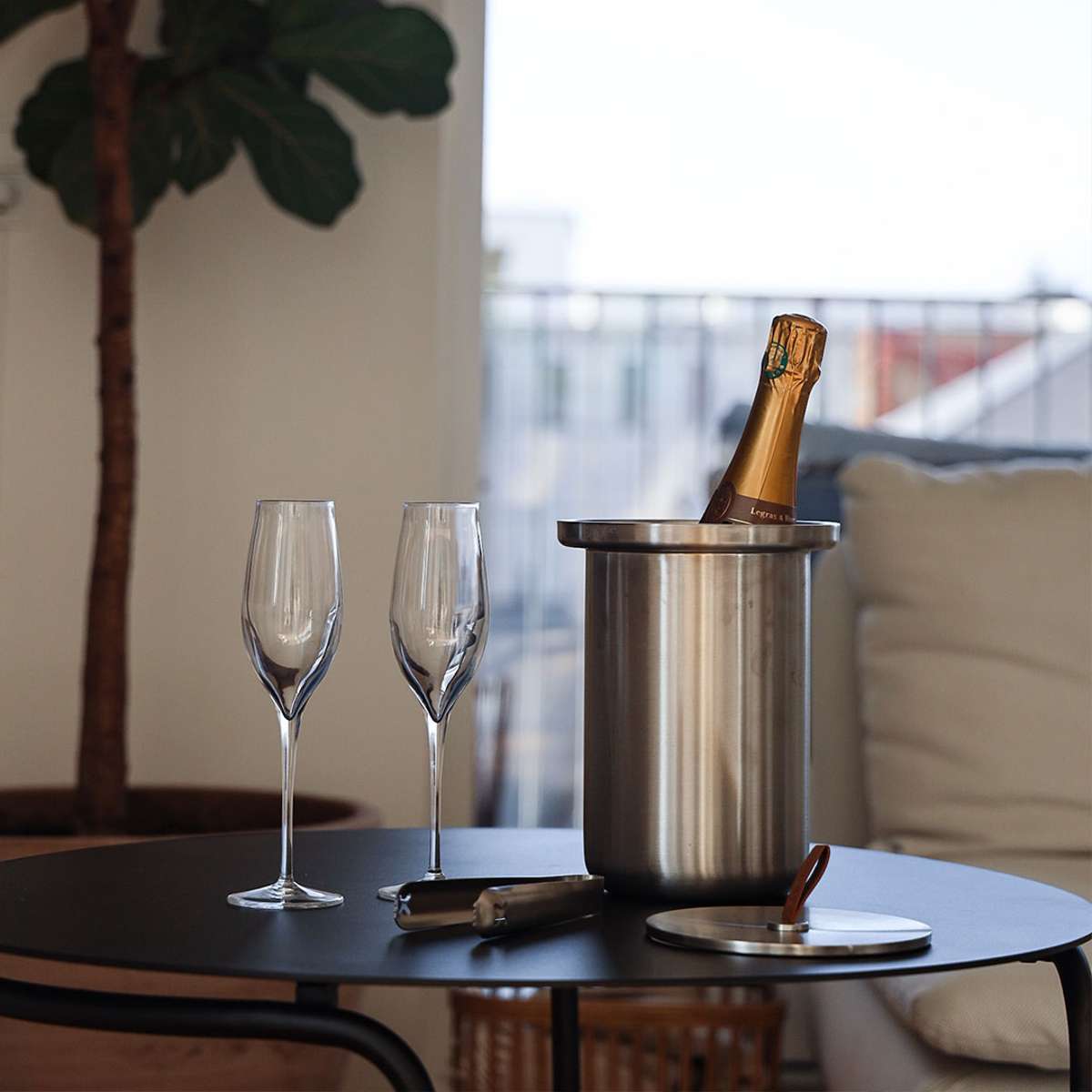 Satin polished stainless steel wine cooler with leather handle and included ice tong on a white background