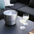 Stainless steel wine bucket with accessories on a white surface, holding ice and bottles.