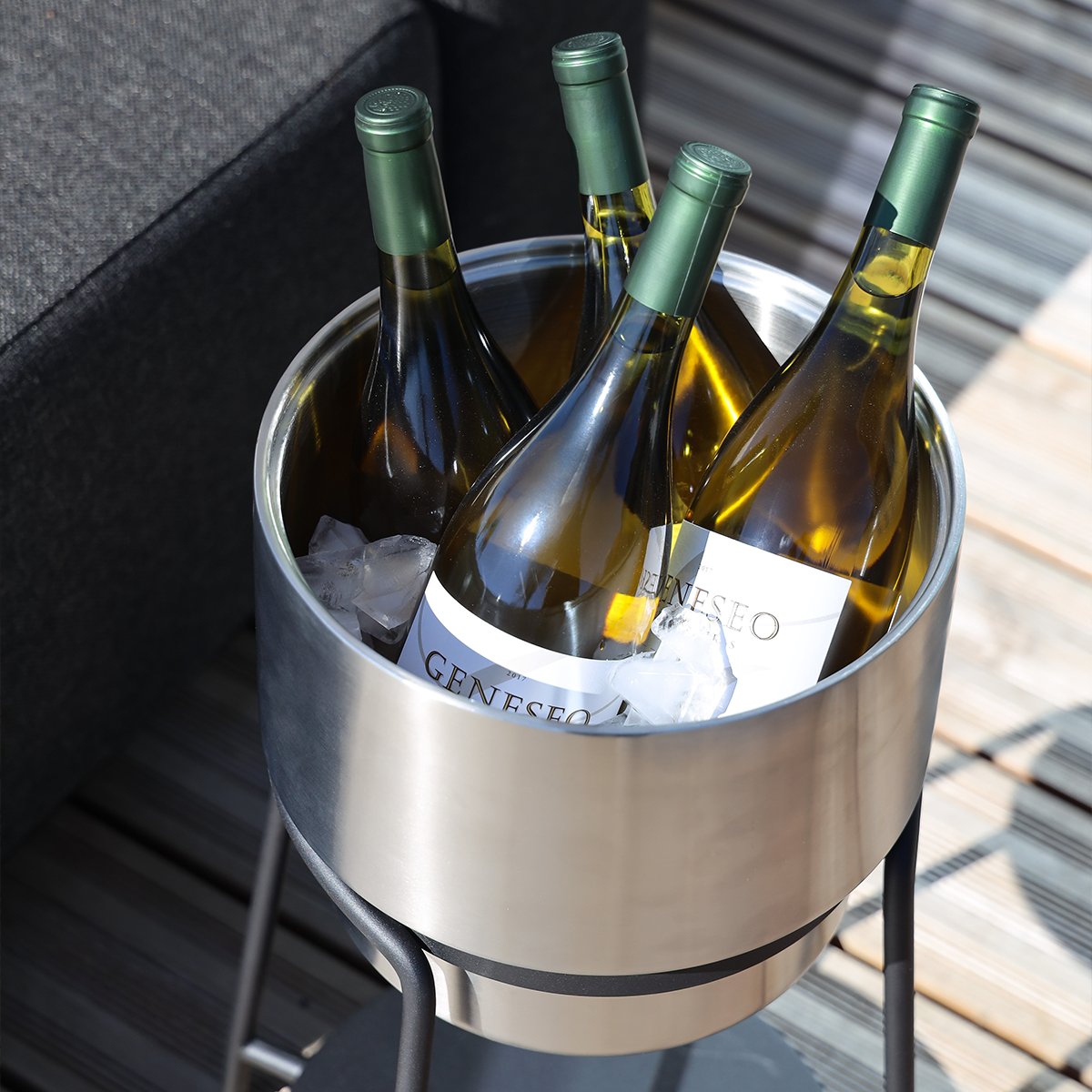 Stainless steel wine bucket with black powder-coated patio accessory stand, both round-shaped.